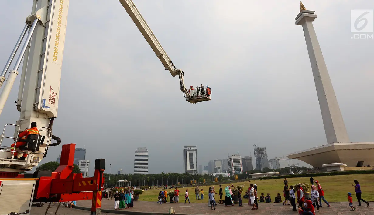 Pengunjung menaiki Bronto Skylift yang disediakan petugas pemadam kebakaran di Monas, Jakarta, Minggu (23/11). Bronto Skylift merupakan fasilitas yang disediakan Pemprov DKI Jakarta untuk melihat Monas dari dekat. (Liputan6.com/JohanTallo)