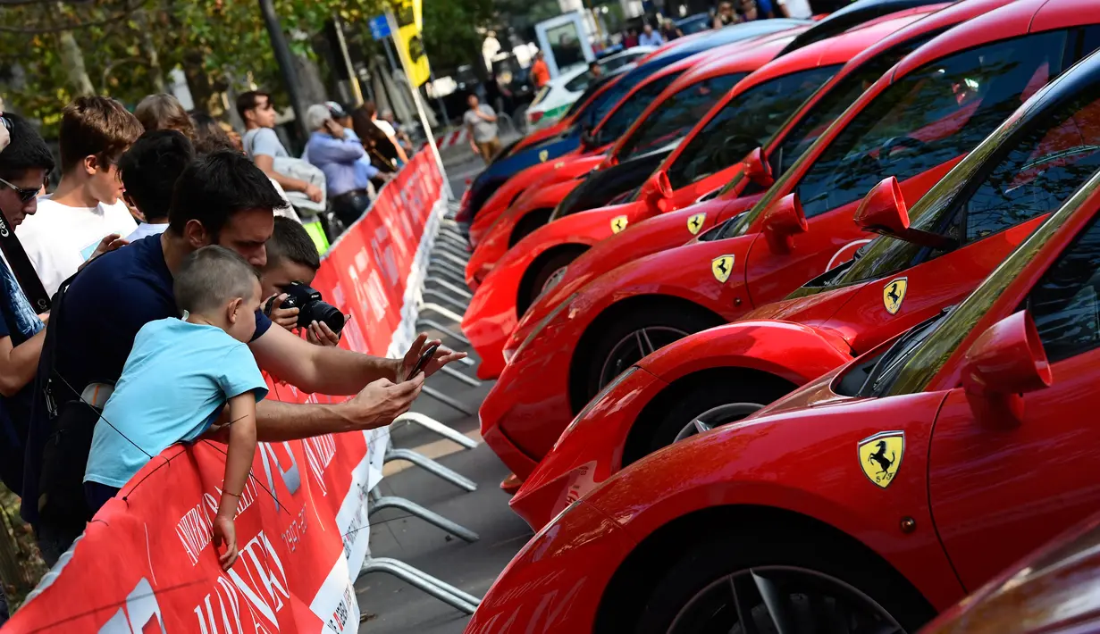 Pengunjung mengambil gambar mobil Ferrari yang dipamerkan saat perayaan ulang tahun Ferrari ke-70 di Corso Sempione di Milan, Italia (8/9). Dalam acara ini sekitar 500 mobil Ferrari dari berbagai tipe pamerkan. (AFP Photo/Miguel Medina)
