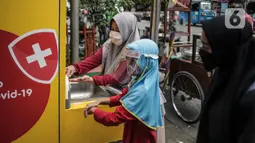 Pengunjung yang mengenakan masker mencuci tangan saat akan masuk Pasar Kebayoran Lama, Jakarta Selatan, Senin (22/6/2020). Pasar Kebayoran Lama menerapkan protokol kesehatan bagi pengunjung dan pedagang untuk mengantisipasi penularan COVID-19. (Liputan6.com/Faizal Fanani)