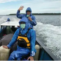 Tim Deru mengenakan jas hujan akibat cuaca yang tidak menentu saat melakukan perjalanan dengan perahu menuju Asmat. (IST/Dok Tim Deru UGM/Solopos.com)