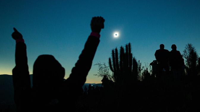 Orang-orang melihat gerhana matahari total dari La Higuera, Chile, Selasa (2/7/2019). Orang-orang bersorak dan bertepuk tangan saat cakram bulan menutup matahari. (AP Photo/Esteban Felix)