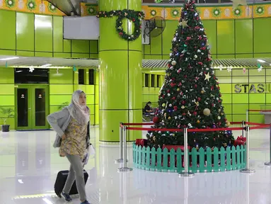 Penumpang melintas di dekat dekorasi pohon Natal di Stasiun Gambir, Jakarta, Jumat (21/12). Dekorasi tersebut dibuat untuk memercantik suasana Stasiun Gambir dalam rangka menyambut Hari Natal dan Tahun Baru 2019. (Liputan6.com/Immanuel Antonius)