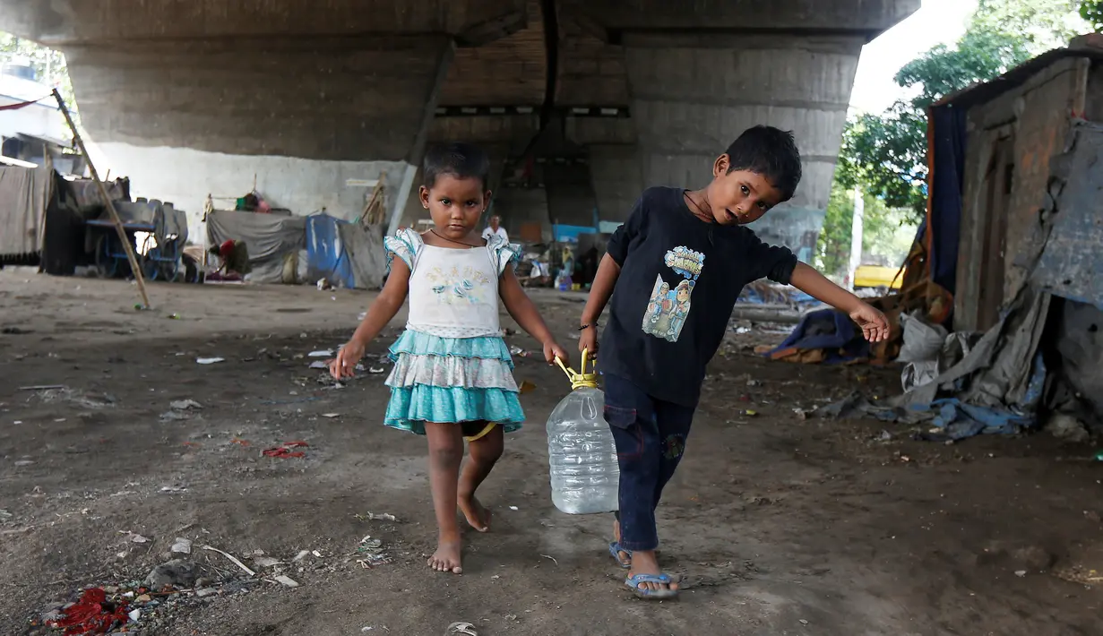 Anak-anak membawa air minum setelah mengisi dari keran kota di bawah jembatan di daerah kumuh di Kalkuta, India (26/5/2016). Kalkuta didirikan Inggris pada 1690 merupakan pusat industri goni dan tekstil. (REUTERS/Rupak De Chowdhuri)