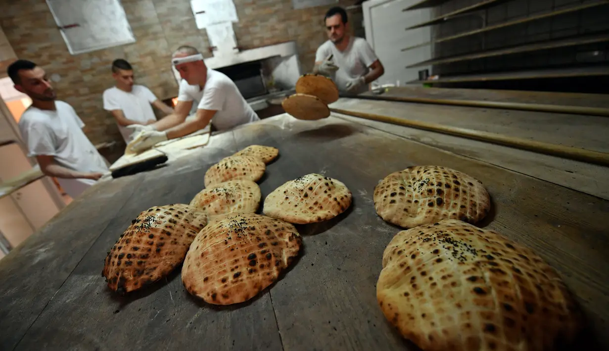 Pekerja membuat somun di sebuah toko roti di kota tua Sarajevo, Bosnia and Herzegovina, Kamis (30/4/2020). Somun merupakan roti tawar tradisional  asal Bosnia yang dibuat sejak abad ke-16 di Sarajevo. (ELVIS BARUKCIC/AFP)