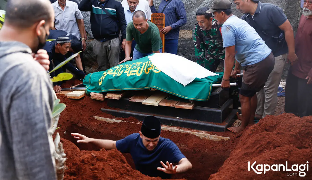 Sebagai anak laki-laki, Ramzi juga turun langsung ke liang lahat untuk membantu proses pemakaman. [Foto: Budy Santoso/KapanLagi.com]