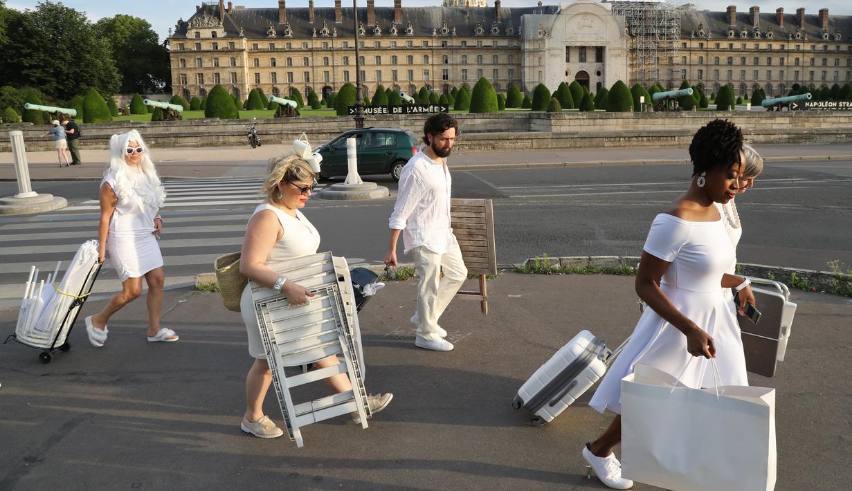 Sejumlah orang berpakaian putih membawa peralatan dan kursi untuk mengikuti makan malam bersama atau "Diner en Blanc" yang ke-30 di Paris, Prancis (3/6). (AFP/Francois Guillot)