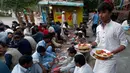 Relawan mendistribusikan makanan berbuka puasa kepada muslim Pakistan di sepanjang jalan di Islamabad pada 7 Mei 2019. Ketika bulan Ramadan mulai di Pakistan, banyak masyarakat muslim memanfaatkan buka puasa gratis yang disponsori oleh badan-badan amal dan orang-orang kaya. (AP/Anjum Naveed)