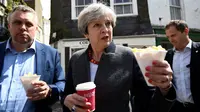 Perdana Menteri (PM), Inggris Theresa May membawa sebungkus keripik saat menemui warga disela kampanyenya di Mevagissey, Cornwall, Selasa (2/5). Theresa May melakukan kampanye dengan berkeliling jalanan di Cornwall. (AFP PHOTO/POOL/DYLAN MARTINEZ)