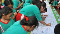 Puluhan murid SD membubuhkan tanda tangan mereka pada sebuah spanduk, Jakarta, Kamis (28/5/2015). Gerakan ini bertujuan untuk memberi dukungan moril bagi atlet Indonesia yang berlaga di Sea Games 2015 Singapura. (Liputan6.com/Herman Zakharia)