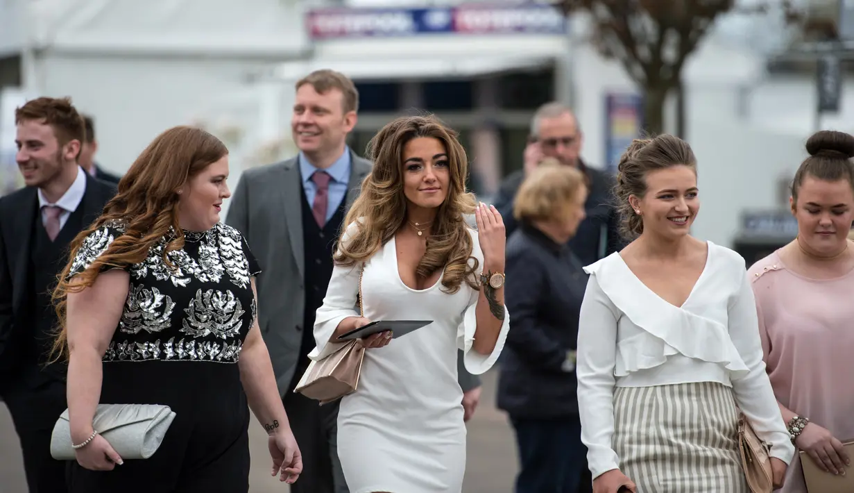 Sejumlah racegoers berdandanan seksi dan modis saat menghadiri Festival Grand National di arena Aintree, Liverpool, Inggris, Jumat (7/4). Kehadiran racegoers memberikan nuansa tersendiri di kompetisi pacuan kuda terbesar tersebut. (AFP Photo / Oli Scarff)