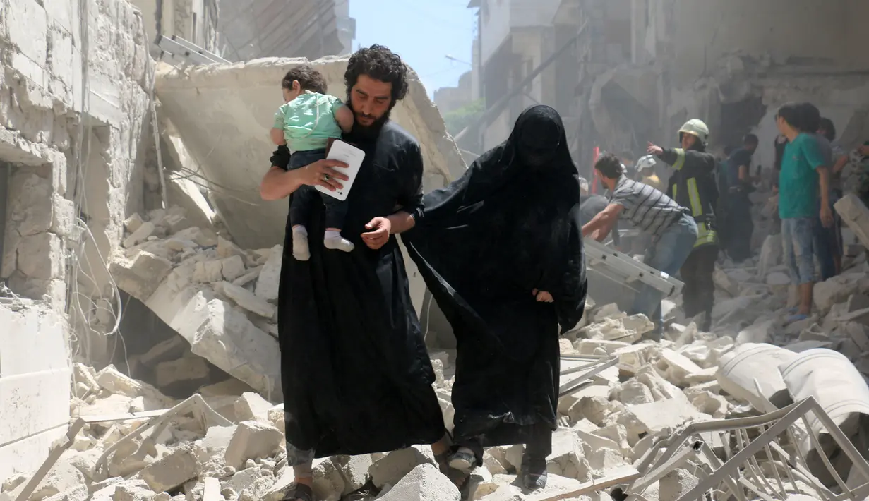 Orang tua berjalan membawa bayinya menyusul serangan udara di kota Suriah bagian utara, Aleppo, Kamis (28/4). Meskipun PBB menetapkan gencatan senjata Februari lalu, jumlah korban tewas terus bertambah. (AFP PHOTO / Ameer ALHALBI)