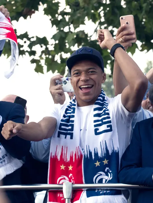 Striker timnas Prancis, Kylian Mbappe berada di atas bus beratap terbuka saat parade merayakan juara Piala Dunia 2018 di sepanjang Champs Elysees, Paris, Senin (16/7). Prancis meraih trofi Piala Dunia kedua usai mengalahkan Kroasia. (AP/Claude Paris)