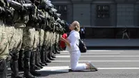Seorang wanita berlutut di depan barisan polisi antihuru-hara saat mereka memblokir demonstrasi pendukung oposisi Belarusia di Minsk, Belarusia, Minggu (30/8/2020). Puluhan ribu demonstran berkumpul untuk menuntut agar Presiden Belarusia Alexander Lukashenko mengundurkan diri. (AP Photo)