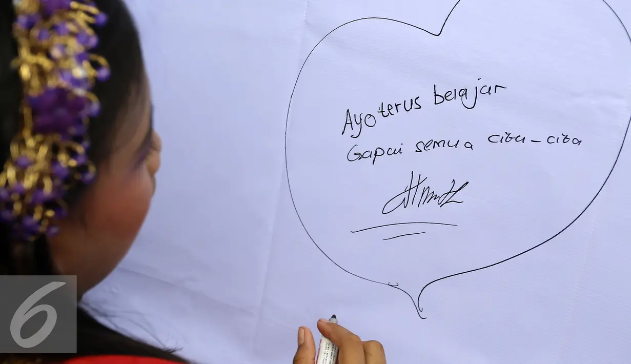 Seorang anak menuliskan testimoni saat Festival Anak Asuh di Car Free Day, Jakarta, Minggu (1/11/2015). Festival ini diikuti 200 lebih anak asuh dari SDN Kebon Sirih. (Liputan6.com/Yoppy Renato)