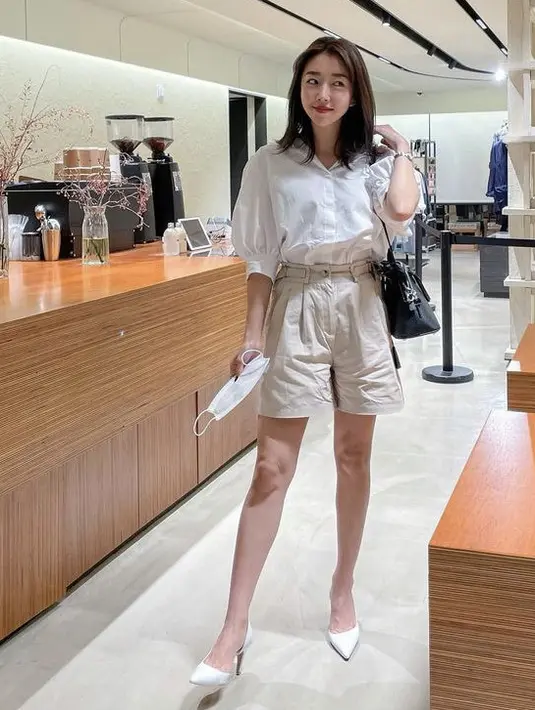 Sunny mengenakan kemeja tangan ballon putih dipadukan dengan short pants warna beige. High hells warna putihnya membuat kakinya terlihat jenjang. Instagram @sunnydahye