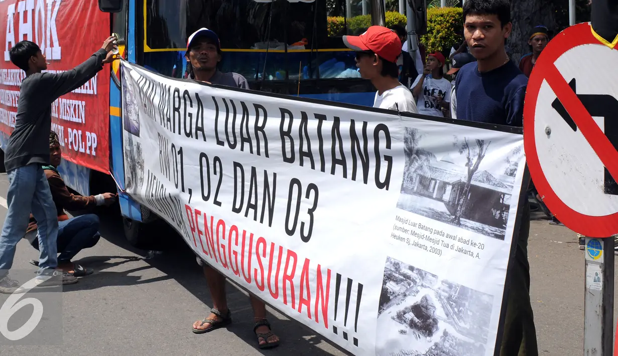 Seorang pemuda kampung Luar Batang memasang spanduk tulisan saat melakukan aksi di depan Balai Kota Jakarta, Jumat (22/4/2016). Mereka mempertanyakan kebijakan Pemprov DKI Jakarta yang melakukan penggusuran. (Liputan6.com/Helmi Fithriansyah)