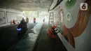 Petugas Penanganan Prasarana dan Sarana Umum (PPSU) menyelesaikan lukisan mural pada tembok kolong Semanggi, Jakarta, Jumat (7/7/2023). Pembuatan mural tersebut guna mempercantik kawasan tersebut yang selalu dilewati pengguna jalan. (Liputan6.com/Faizal Fanani)