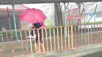 Anak perempuan gendong teman sekolahnya yang autis saat hujan. (dok. screenshot video Facebook @autisme.malaysia)