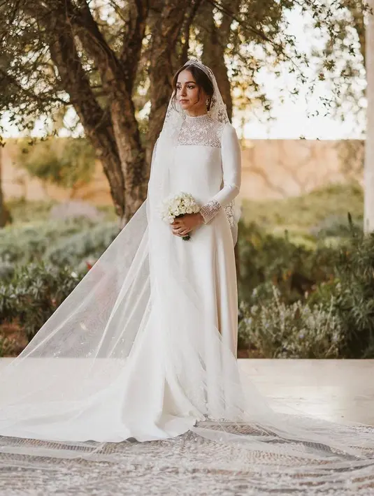 Putri Iman dari Yordania tampil mengenakan gaun putih panjang beraksen lace di bagian leher dari Dior. [@dior]