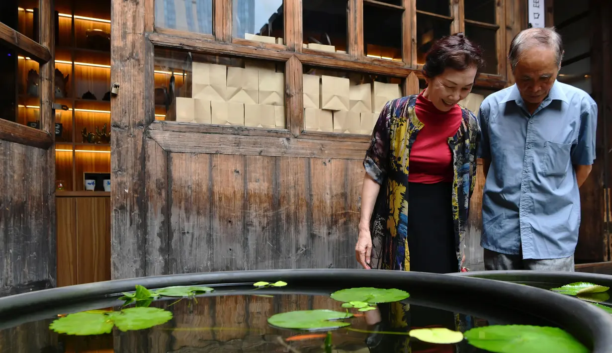 Para pengunjung mengamati ikan mas hias di sebuah museum di Sanfangqixiang (Tiga Jalur dan Tujuh Lorong), Kota Fuzhou, Provinsi Fujian, China, 23 September 2020. Lebih dari 3.000 ikan mas hias dari sekitar 100 spesies dipamerkan di museum tersebut. (Xinhua/Wei Peiquan)
