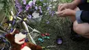 Salah satu warga meletakkan untaian bunga dan mainan anak di dekat lokasi jatuhnya pesawat Malaysia Airlines MH-17 di Donetsk, Ukraina, (19/7/2014). (REUTERS/Maxim Zmeyev)