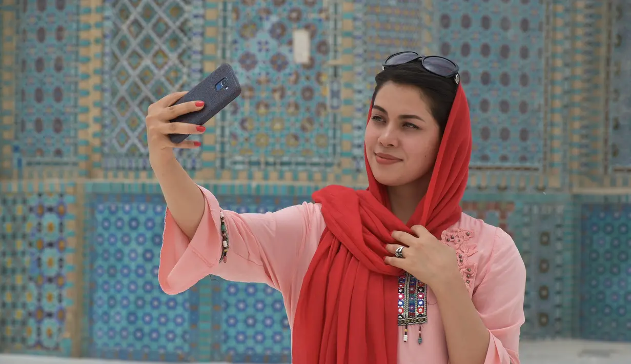 Seorang wanita berswafoto dengan latar belakang Masjid Biru di Mazar-i-Sharif, ibu kota Provinsi Balkh, Afghanistan utara (11/7/2020). Setelah lima bulan ditutup akibat dampak pandemi COVID-19, Masjid Biru baru-baru ini telah dibuka kembali untuk umum. (Xinhua/Kawa Basharat)