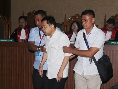 Tersangka korupsi e-KTP, Setya Novanto dipapah petugas saat memasuki ruang sidang Pengadilan Tipikor, Jakarta, Rabu (13/12). Sidang tersebut dipimpin oleh Ketua Majelis Hakim Yanto. (Liputan6.com/Helmi Fithriansyah)