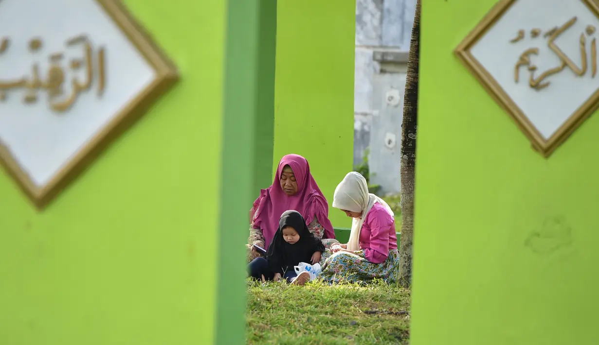 Warga berdoa saat melakukan ziarah di Kuburan Massal Ulee Lheue selama peringatan 14 tahun tsunami Aceh di Banda Aceh, Rabu (26/12). Sejumlah warga mengenang keluarga yang meninggal akibat bencana tsunami di Aceh 14 tahun silam. (Chaideer MAHYUDDIN / AFP)