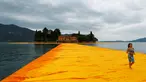 Seorang wanita berjalan diatas instalasi seni 'The Floating Piers' buatan seniman kelahiran Bulgaria Christo Vladimirov Yavachev atau dikenal sebagai Christo , di Danau Iseo , Italia utara , (16/6). (REUTERS / Stefano Rellandini)