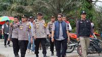 Kapolres Pelalawan AKBP Suwinto bersama polisi lainnya menuju TPS untuk melihat proses pencoblosan. (Liputan6.com/M Syukur)