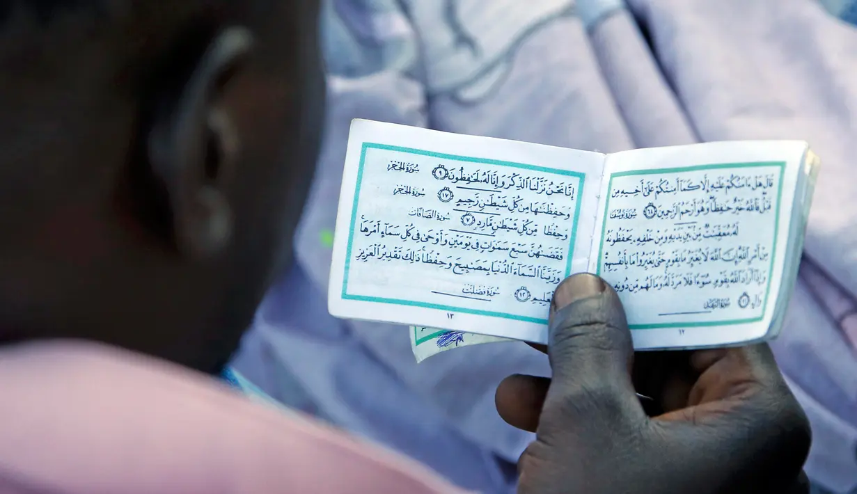 Al-Quran berukuran kecil saat dibaca seorang imigran di Saint Ludovic perbatasan Italia-Prancis, (18/6/2015). Sekitar 200 imigran berada di bebatuan pantai untuk melintasi perbatasan Italia. (REUTERS/Eric Gaillard)