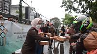 Dibantu beberapa staf kejaksaan, Kajari Garut, Neva Sari Susanti langsung memimpin pembagian paket takjil ramadan 2022 kepada pengguna jalan di depan kantor Kejari Garut, Senin petang. (Liputan6.com/Jayadi Supriadin)