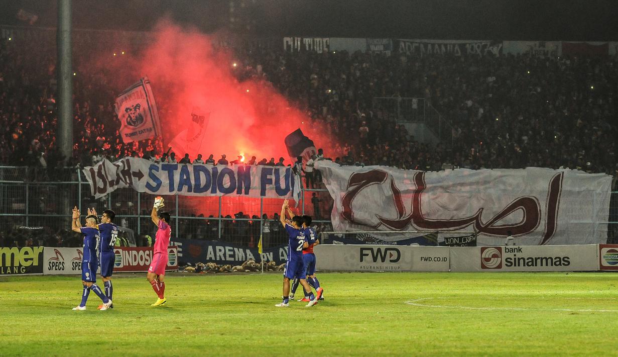 Suporter Arema Indonesia menyalakan flare usai laga semifinal leg pertama Piala Presiden di Stadion Kanjuruhan, Malang, Sabtu (3/10/2015). Arema imbang dengan Sriwijaya FC 1-1. (Bola.com/Kevin Setiawan)