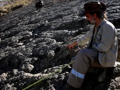 Paleontolog Sebastian Apesteguia mengukur jejak kaki dinosaurus yang ditemukan di Maragua, Bolivia (21/7). Jejak kaki dinosaurus diduga berusia 80 juta tahun tersebut berdiameter 1,2 meter. (REUTERS/ David Mercado)