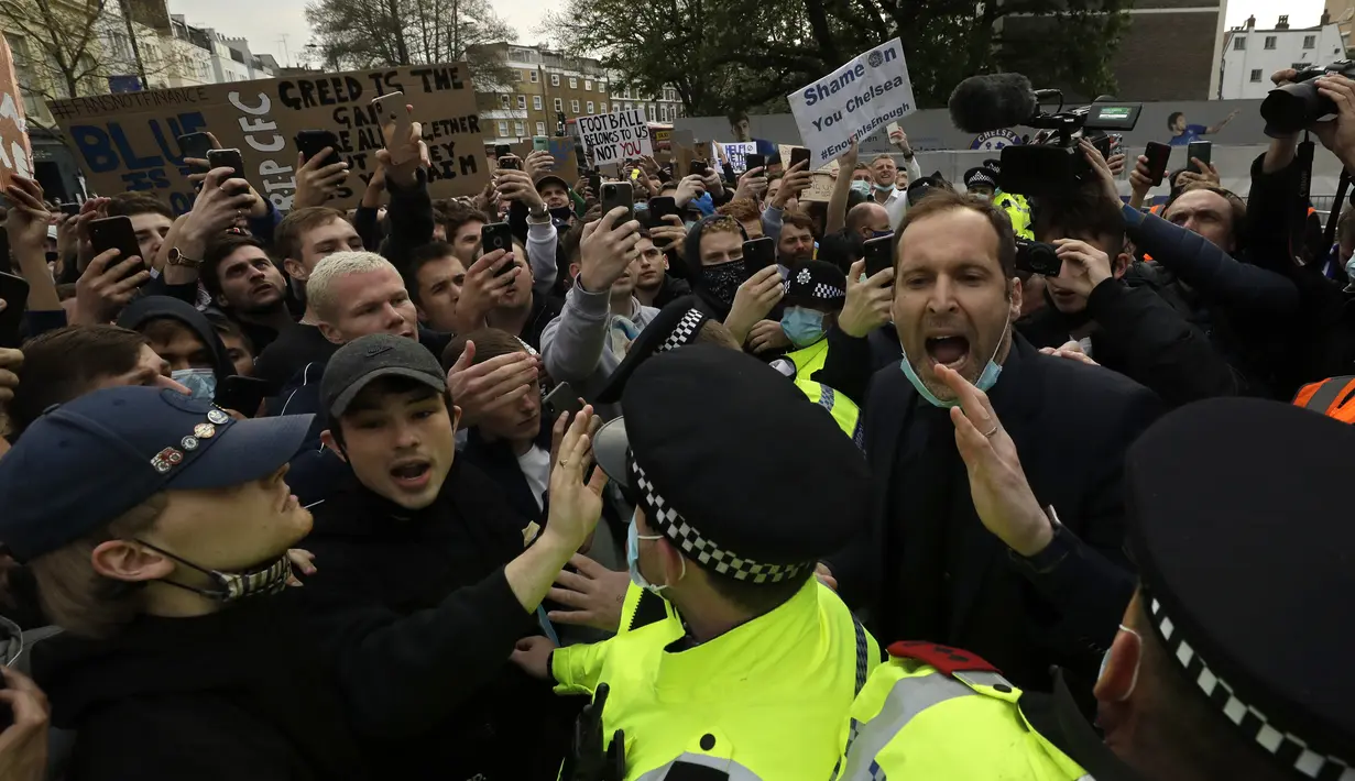 Mantan kiper Chelsea Petr Cech (kanan) berdiri di belakang barisan polisi mencoba menenangkan para fans yang melakukan aksi protes menentang keputusan Chelsea ikut serta dalam pembentukan Liga Super Eropa di luar Stadion Stamford Bridge, London, Inggris, Selasa (20/4/2021). (AP Photo/Matt Dunham)