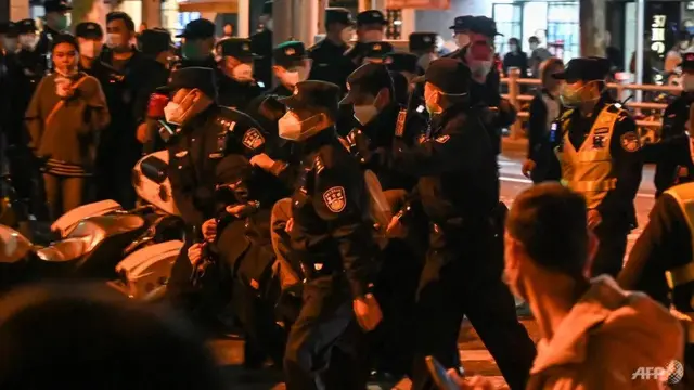 Seorang pria ditangkap saat orang-orang berkumpul di sebuah jalan di Shanghai pada 27 November 2022. (Foto: AFP/Hector Retamal)