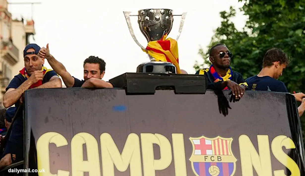Beberapa pemain Barcelona berdiri di atas bus berikut dengan trophy La Liga.