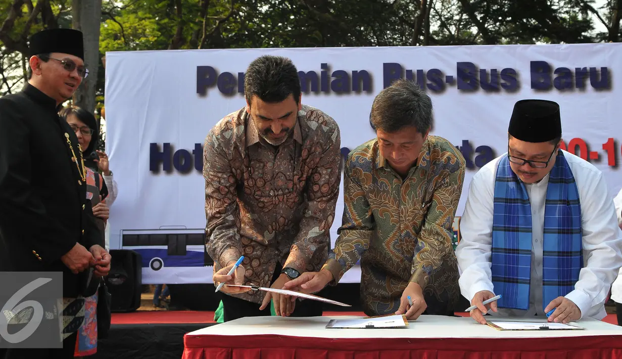 Basuki T Purnama (kiri) menyaksikan penandatanganan saat peluncuran bus-bus baru dan hotline Transjakarta di monas, Jakarta, Senin (22/6/2015). Sebanyak 20 unit bus gandeng Transjakarta buatan eropa resmi diluncurkan. (Liputan6.com/Herman Zakharia)