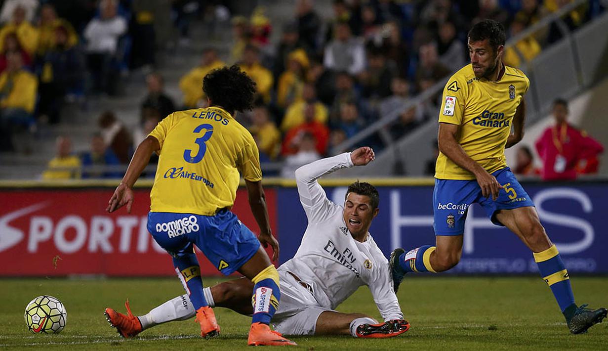Penyerang Real Madrid, Cristiano Ronaldo, terjatuh akibat berebut bola dengan gelandang Las Palmas, Mauricio Lemos. Sementara bagi Las Palmas kekalahan ini membuat mereka turun ke peringkat 15. (Reuters/Juan Medina)
