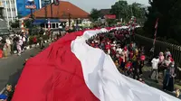 Warga Kota Bogor mengarak bendera merah putih raksasa. Kegiatan kirab ini digelar dalam rangkaian Festival Merah Putih (FMP) yang diselenggarakan selama satu bulan untuk menyemarakkan HUT ke-78 Kemerdekaan RI. (Liputan6.com/Achmad Sudarno)
