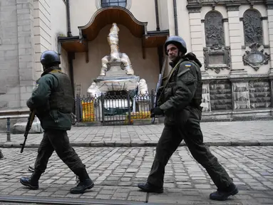Prajurit Ukraina berjalan melewati patung-patung yang dibungkus di Katedral Latin di Lviv, 5 Maret 2022. Di tengah meningkatnya konflik antara Rusia dan Ukraina, warga kota Lviv membungkus semua patung di kota itu untuk melindungi warisan sejarahnya dari kemungkinan serangan. (Daniel LEAL/AFP)