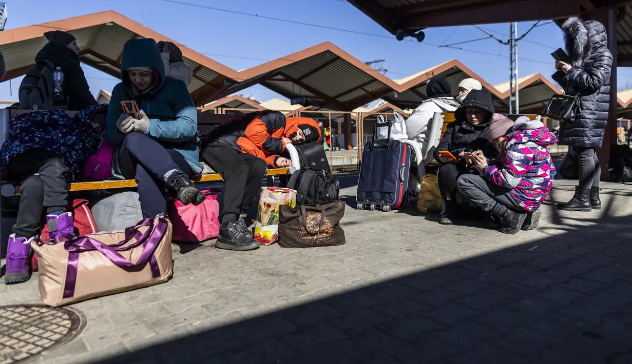 Pengungsi terlihat saat mereka menunggu transportasi lebih lanjut di stasiun kereta api di Przemysl, Polandia pada 17 Maret 2022. Lebih dari tiga juta warga Ukraina telah melarikan diri melintasi perbatasan, kebanyakan perempuan dan anak-anak, menurut PBB. (Wojtek RADWANSKI/AFP)