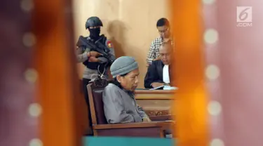 Terdakwa sejumlah kasus tindak pidana terorisme, Aman Abdurrahman saat mengikuti pembacaan tuntutan JPU di PN Jakarta Selatan, Jumat (18/5). Sidang dijaga ketat puluhan personel gabungan bersenjata lengkap. (Liputan6.com/Helmi Fithriansyah)