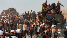 Orang-orang naik ke atas dan bergelantungan di atas truk yang mengangkut mereka, sementara yang lain berjalan sambil membawa karung-karung tepung di sepanjang jalan al-Rashid di Jabalia Barat pada 17 Juni 2025. (BASHAR TALEB/AFP)