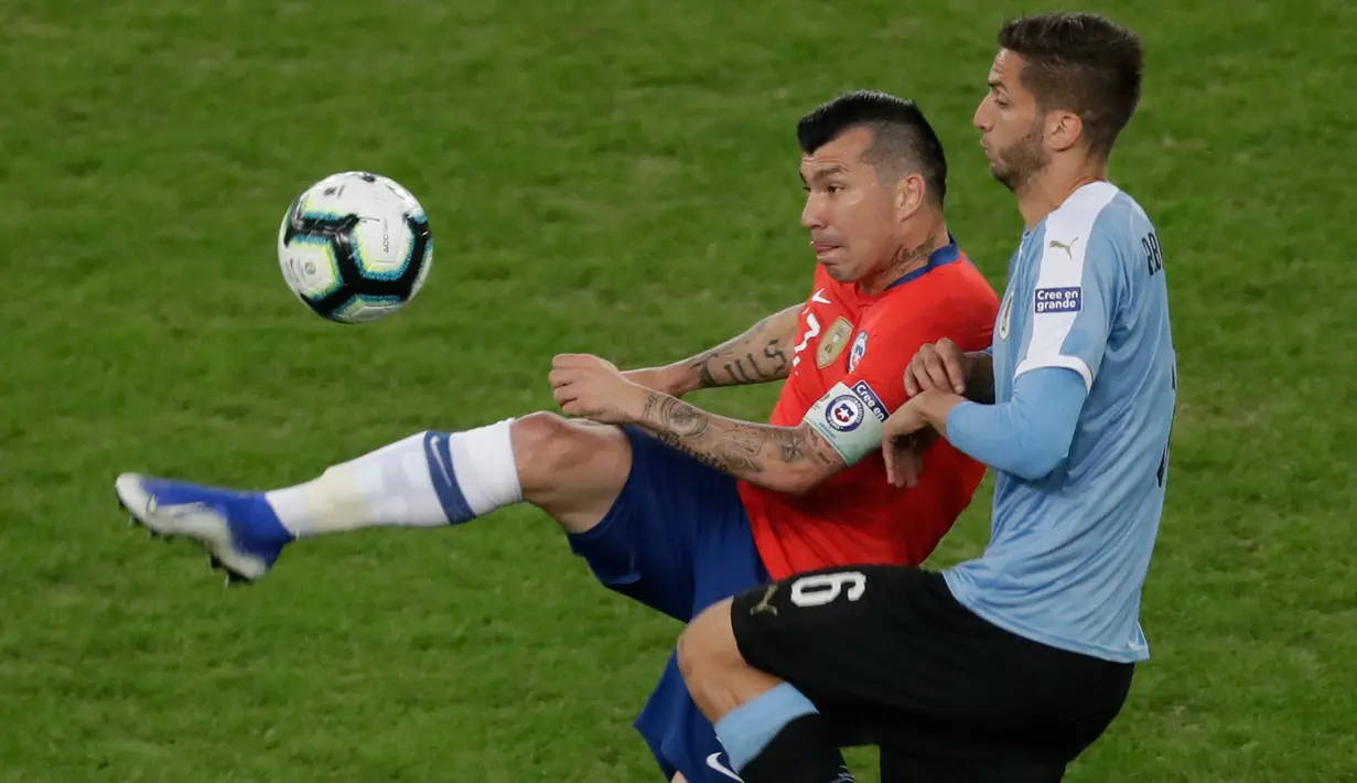 Pemain timnas Chile, Gary Medel dari Cile berebut bola dengan gelandang Uruguay, Rodrigo Bentancur pada laga terakhir grup C Copa America 2019 di stadion Maracana, Senin (24/6/2019). Uruguay berhasil melaju ke perempatfinal dengan status juara Grup C usai mengalahkan Chile 1-0. (AP/Eraldo Peres)
