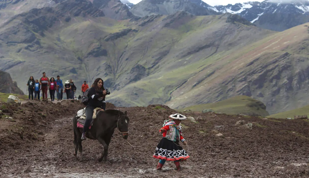 Seorang turis wanita menunggang kuda saat berwisata di Gunung Pelangi di Pitumarca, Peru (2/4). Rainbow Mountain atau Gunung Pelangi terbentuk sekitar 24 juta tahun lalu, akibat gempa tektonik. (AP Photo/Martin Mejia)