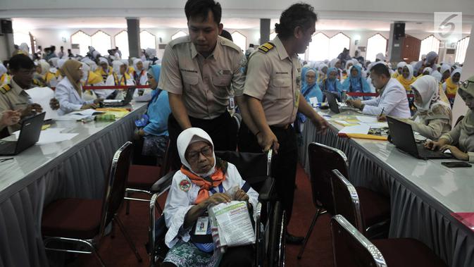 Petugas menuntun salah seorang calon jemaah haji lansia saat menjalani tes kesehatan di Asrama Haji Pondok Gede, Jakarta, Senin (16/7). Sebanyak 388 calon jemaah haji asal Jakarta Timur telah mulai masuk ke asrama. (Merdeka.com/Iqbal Nugroho)