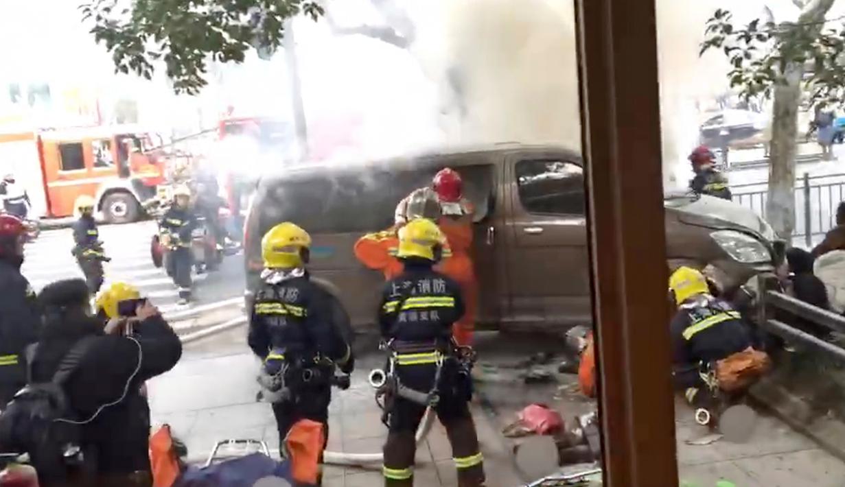 Pemadam kebakaran memadamkan api dari sebuah van yang menabrak para pejalan kaki di trotoar daerah sibuk di Shanghai, China, Jumat (2/2). Namun, tidak dijelaskan apakah kebakaran berlangsung sebelum atau saat insiden terjadi. (AP Photo)
