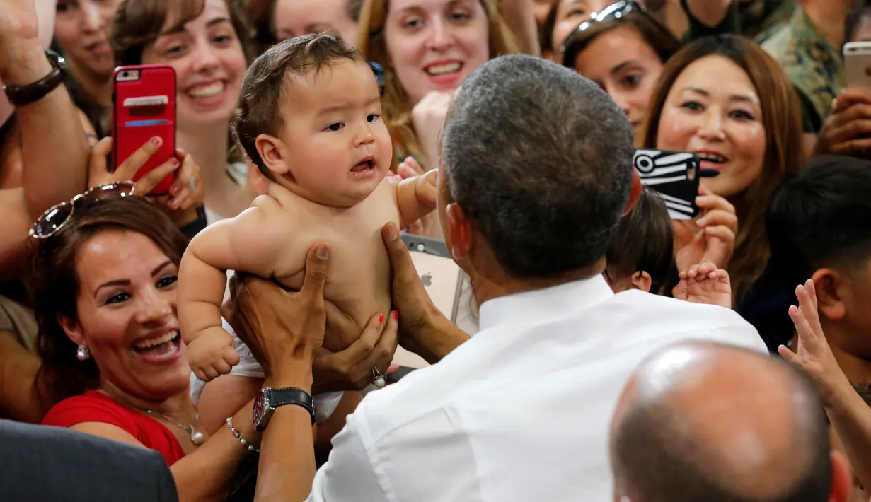 Presiden AS Barack Obama memegang bayi selama kunjungannya di Stasiun Udara Korps Marinir Iwakuni, Jepang (27/5). Kedatangan Obama ke Jepang untuk mennghadiri pertemuan G7. (REUTERS/Carlos Barria)