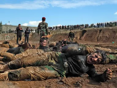 Pasukan perempuan Peshmerga menggulingkan badannya di tanah saat berlatihan dalam upacara kelulusan di Kota Soran, Irak, Rabu (12/2/2020). Latihan militer pasukan bersenjata Kurdi tersebut dilakukan sekitar 100 kilometer timur laut ibu kota otonomi wilayah Kurdi di Irak, Arbil. (SAFIN HAMED/AFP)